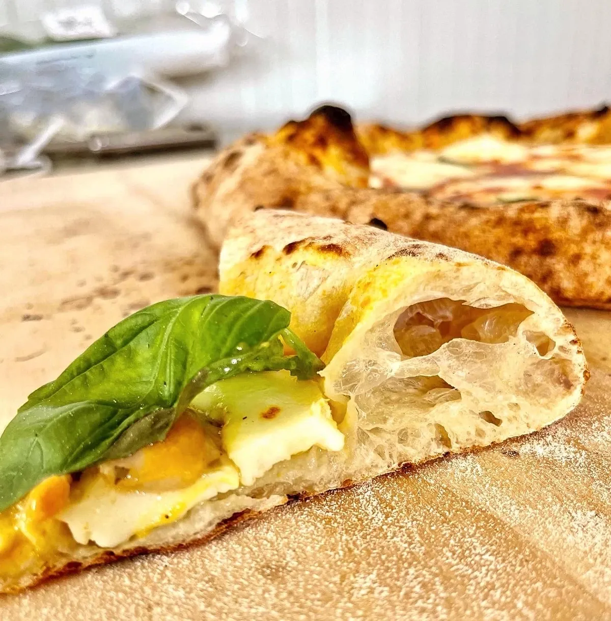 Angeschnittene Fermento Pizza mit luftigem Rand und Basilikum